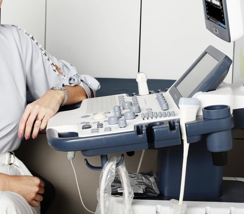 Mão da Dra. Michelle Sanches apoiada no painel do aparelho de ecocardiograma